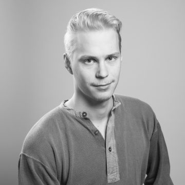 Mustavalkoinen muotokuva nuoresta miehestä, jolla on vaaleat, taaksepäin muotoillut hiukset. Hänellä on päällään napitettu pitkähihainen paita ja hän katsoo suoraan kameraan neutraalilla ilmeellä tavallista taustaa vasten.