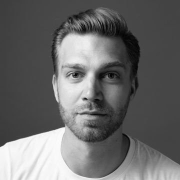 Mustavalkoinen muotokuva miehestä, jolla on vaaleat, siististi laitetut hiukset, lyhyt parta ja viikset. Hänellä on yllään tavallinen vaalea paita ja hän katsoo suoraan kameraan neutraalilla ilmeellä.