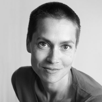 Mustavalkoinen muotokuva henkilöstä, jolla on lyhyet hiukset, vaaleat silmät ja hento hymy, ja joka katsoo suoraan kameraan. Hänellä on yllään tavallinen paita ja hänet on kuvattu tavallista taustaa vasten.