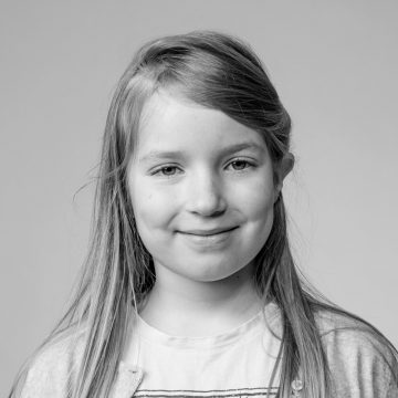 Nuori tyttö, jolla on pitkät, suorat hiukset, hymyilee lempeästi kameralle. Hänellä on yllään vaalea paita ja villatakki. Kuva on mustavalkoinen, ja siinä on tavallinen tausta.