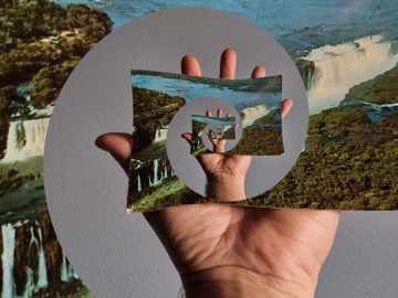 Käsi pitelee vesiputouskuvasta leikattua leikkausta, jossa on kierrevaikutelma, mikä luo visuaalisen illuusion siitä, että käsi ja kuva toistuvat loputtomasti keskelle.