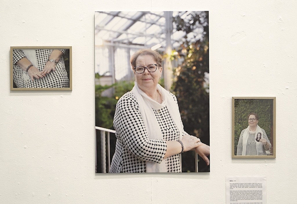 Gallerian seinällä on kolme kehystettyä valokuvaa vanhemmasta silmälasipäisestä naisesta, jolla on kuvioitu mekko ja valkoinen huivi, sekä lyhyt kuvaus. Keskimmäisessä kuvassa nainen seisoo kasvihuoneen kaiteen vieressä.