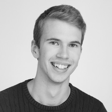 Lyhyet, vaaleanruskeat hiukset omaava nuori mies hymyilee kameralle. Hänellä on yllään tumma, kuvioitu villapaita, ja hän on poseerannut vaaleaa taustaa vasten. Kuva on mustavalkoinen.
