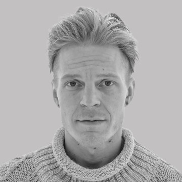 Henkilö, jolla on lyhyet, vaaleat hiukset ja neutraali ilme, päällään vaalea, paksu neulottu villapaita, kuvattuna vaaleanharmaata taustaa vasten.
