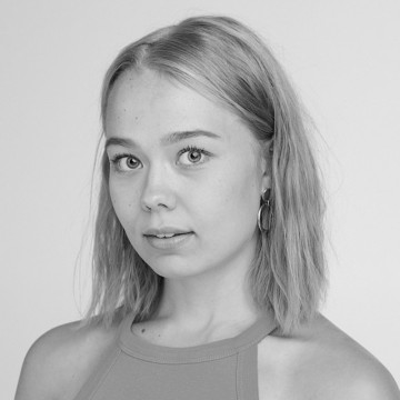 Nuori nainen, jolla on suorat, olkapään pituiset vaaleat hiukset ja korvakorut, katsoo kameraan neutraalilla ilmeellä. Hänellä on yllään hihaton toppi. Kuva on mustavalkoinen.