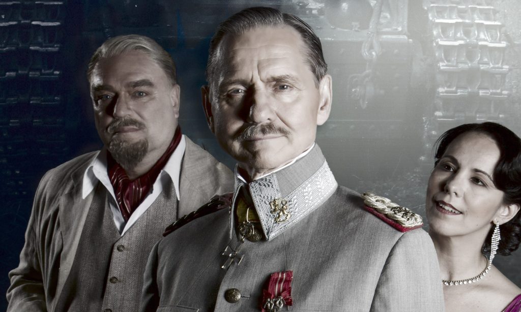 Kolme vintage-asuihin pukeutunutta aikuista poseeraa yhdessä. Edessä olevalla miehellä on koristeltu sotilasunivormu, hänen takanaan olevalla miehellä on puku ja punainen huivi, ja oikealla oleva nainen hymyilee muodollisesti pukeutuneena. Tausta on sumea ja tumma.