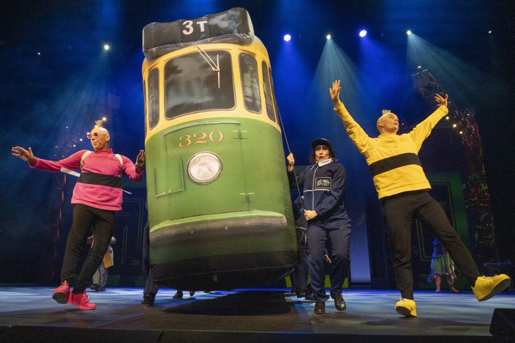 Lavalla esiintyy neljä värikkäisiin pukuihin pukeutunutta esiintyjää, joista kaksi pitää kädessään suurta vihreää raitiovaunua, jossa on merkintä 320. Kirkas näyttämövalaistus ja dramaattiset asennot luovat energisen teatterikohtauksen.