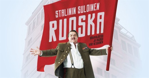 Sotilaspukuinen mies seisoo rakennuksen edessä ja pitää kädessään suurta punaista lippua, jossa lukee rohkeilla valkoisilla kirjaimilla Stalinin Suloinen Ruoska. Mies näyttää huutavan tai tekevän voimakkaan eleen.