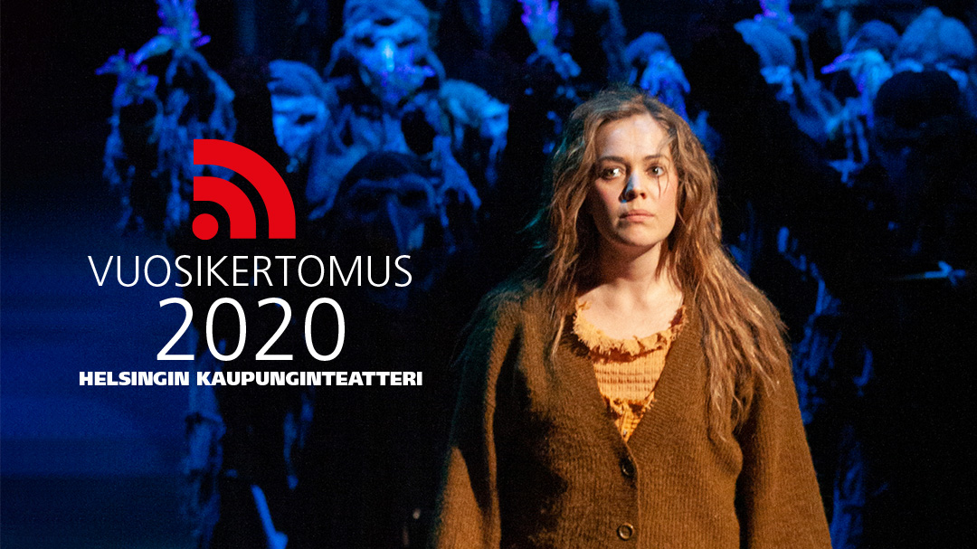 Ruskeaan villapaitaan pukeutunut nainen seisoo lavalla dramaattisessa valaistuksessa, ja hänen takanaan on ihmisjoukko sinisessä valossa. Tekstissä lukee: Vuosikertomus 2020 Helsingin Kaupunginteatteri.