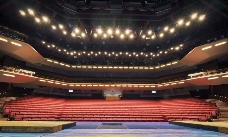 Näkymä näyttämöltä, josta avautuu näkymä tyhjään teatterisaliin, jossa on punaisia penkkirivejä, kolmessa kerroksessa parvekkeita ja kirkkaat näyttämövalot valaisevat tilaa.
