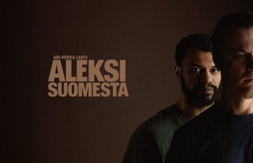 Kaksi miestä seisoo tummaa taustaa vasten; toinen, jolla on lyhyet kiharat hiukset ja parta, katsoo eteenpäin, kun taas toinen, osittain näkyvä, seisoo edessä. Isossa tekstissä lukee "ALEKSI SUOMESTA" ja sen yläpuolella on pienempi teksti.